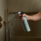 Guests on Earth All-Purpose Cleaner sprayed on a glass shower door, cutting soap scum with a refillable bottle