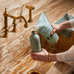 Guests on Earth Dish Soap refill poured from pouch into reusable bottle at a marble sink for low-waste kitchen clean-up