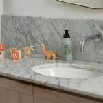 Guests on Earth Foaming Hand Soup on a marble vanity beside kids’ toys, styled by a chrome faucet and sink
